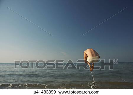 Mid adult man bombing into sea View Large Photo Image Stock Photo - Mid adult man bombing into sea. Fotosearch