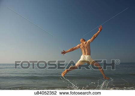 Mid adult man jumping outstretched over sea View Large Photo Image Stock Image - Mid adult man jumping outstretched over sea. Fotosearch