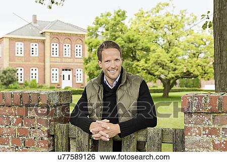 Mid adult man leaning on wooden gate View Large Photo Image Stock Photograph - Mid adult man leaning on wooden gate. Fotosearch
