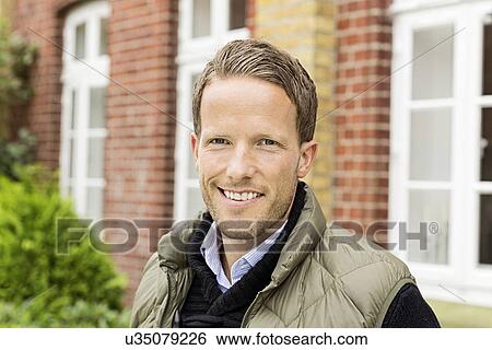 Stock Photograph - Mid adult man smiling towards camera. Fotosearch