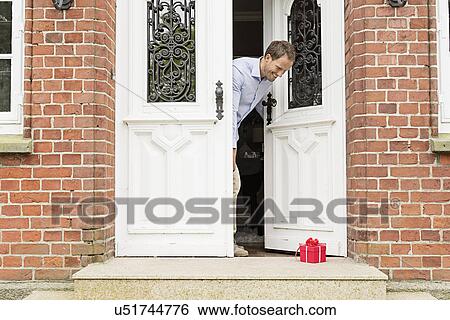 Mid adult man with gift on front doorstep View Large Photo Image Stock Photograph - Mid adult man with gift on front doorstep. Fotosearch