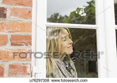 Mid adult woman by window with eyes closed, smiling View Large Photo Image Stock Photo - Mid adult woman by window with eyes closed, smiling. Fotosearch