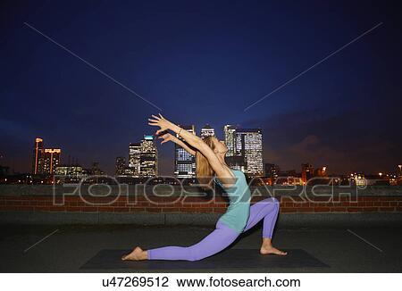 Mid adult woman doing yoga on city rooftop at night View Large Photo Image Stock Image - Mid adult woman doing yoga on city rooftop at night. Fotosearch