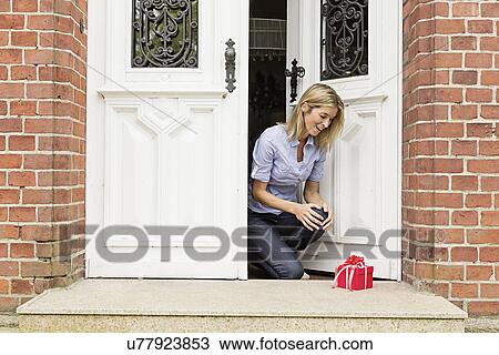 Mid adult woman with gift on front doorstep View Large Photo Image Stock Image - Mid adult woman with gift on front doorstep. Fotosearch