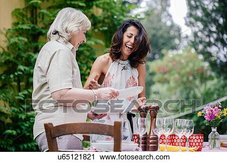 Mother and adult daughter setting table for family meal View Large Photo Image Stock Image - Mother and adult daughter setting table for family meal. Fotosearch