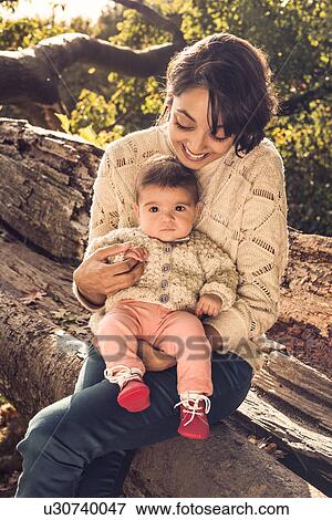 Stock Photo - Mother and baby sitting on log. Fotosearch