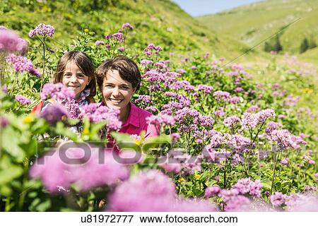 Stock Photo - Mother and daughter hiding among wild flowers, Tyrol, Austria. Fotosearch