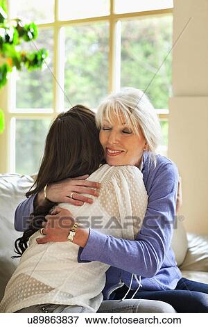 Mother and daughter hugging on sofa View Large Photo Image Stock Photo - Mother and daughter hugging on sofa. Fotosearch