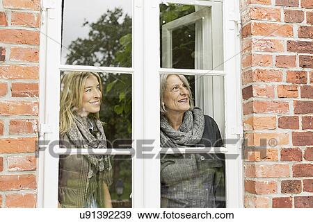 Mother and daughter looking through window View Large Photo Image Stock Photo - Mother and daughter looking through window. Fotosearch