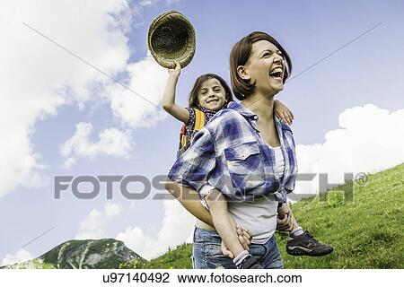 Stock Image - Mother and daughter on hike, girl holding straw hat. Fotosearch