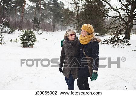 Stock Image - Mother and daughter walking in snow. Fotosearch