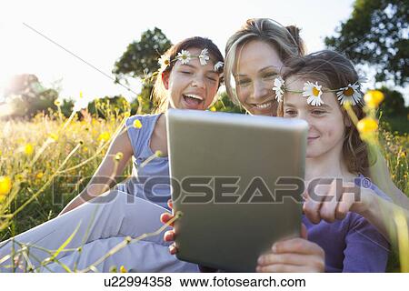Mother and daughters in field using digital tablet View Large Photo Image Stock Photo - Mother and daughters in field using digital tablet. Fotosearch