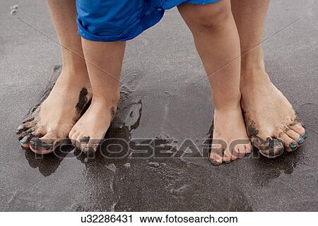 Stock Image - Mother and son standing on wet sand. Fotosearch