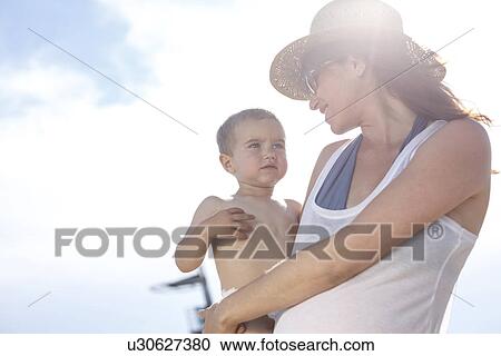 Stock Image - Mother carrying son in arms. Fotosearch