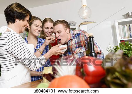 Stock Image - Mother, daughters and son tasting food. Fotosearch