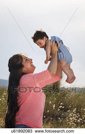 Mother holding baby in midair View Large Photo Image Stock Image - Mother holding baby in midair. Fotosearch