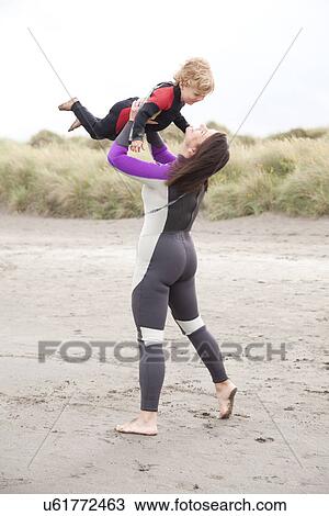 Mother lifting son on beach View Large Photo Image Stock Image - Mother lifting son on beach. Fotosearch