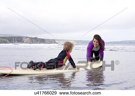 Mother teaching son how to surf View Large Photo Image Stock Photo - Mother teaching son how to surf. Fotosearch