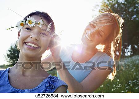 Mother tying daisy chain around daughter's head View Large Photo Image Picture - Mother tying daisy chain around daughter's head. Fotosearch