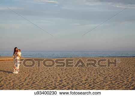 Mother walking along beach, carrying toddler View Large Photo Image Stock Image - Mother walking along beach, carrying toddler. Fotosearch