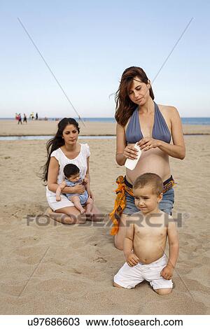 Mothers and babies on beach, mother holding bottle of suncream View Large Photo Image Stock Image - Mothers and babies on beach, mother holding bottle of suncream. Fotosearch