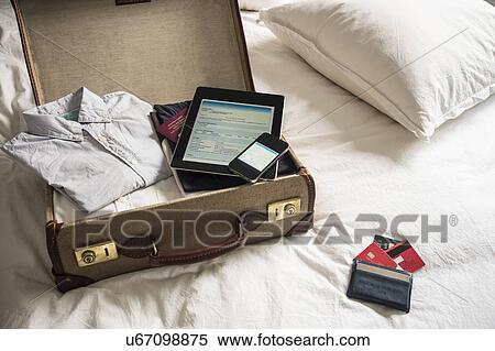 Open suitcase on bed with digital tablet and mobile phone View Large Photo Image Stock Photography - Open suitcase on bed with digital tablet and mobile phone. Fotosearch