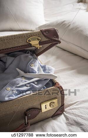 Open suitcase on bed with shirt and toy airplane View Large Photo Image Stock Photo - Open suitcase on bed with shirt and toy airplane. Fotosearch