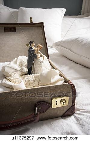 Open suitcase on bed with wedding figurines View Large Photo Image Stock Photo - Open suitcase on bed with wedding figurines. Fotosearch