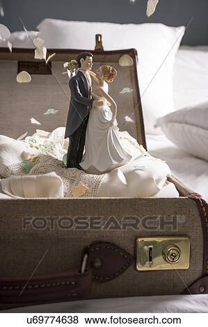 Open suitcase on bed with wedding figurines and confetti View Large Photo Image Stock Photo - Open suitcase on bed with wedding figurines and confetti. Fotosearch