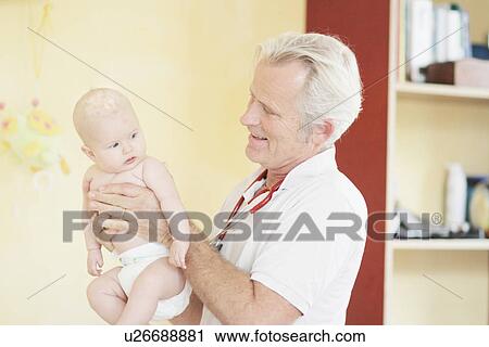 Paediatrician examining baby girl, holding baby View Large Photo Image Stock Image - Paediatrician examining baby girl, holding baby. Fotosearch