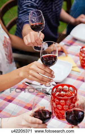 Stock Image - People raising glasses of red wine. Fotosearch