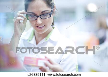 Stock Image - Pharmacist looking at box of medication. Fotosearch