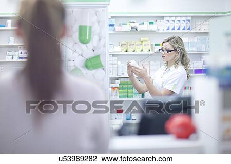 Pharmacist looking at box of medication View Large Photo Image Stock Image - Pharmacist looking at box of medication. Fotosearch