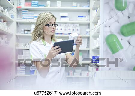 Pharmacist looking at digital tablet and medication View Large Photo Image Stock Photo - Pharmacist looking at digital tablet and medication. Fotosearch