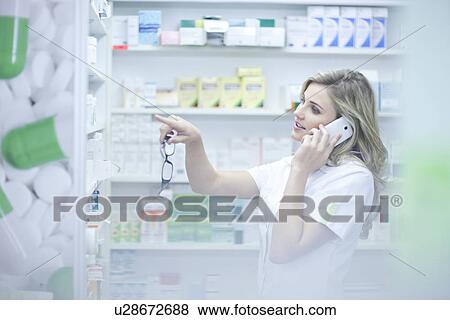 Stock Photo - Pharmacist on phonecall and pointing to medication. Fotosearch