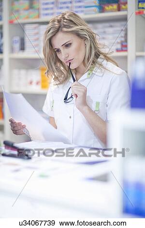 Stock Photo - Pharmacist reading paperwork. Fotosearch