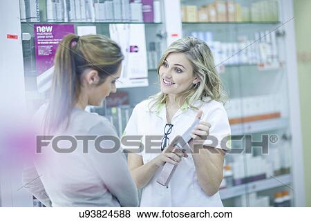 Stock Photo - Pharmacist showing customer box of medication. Fotosearch
