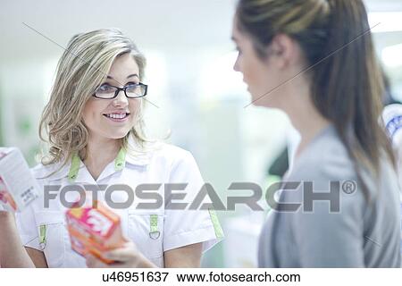 Pharmacist talking to customer, holding boxes of vitamins View Large Photo Image Stock Photo - Pharmacist talking to customer, holding boxes of vitamins. Fotosearch