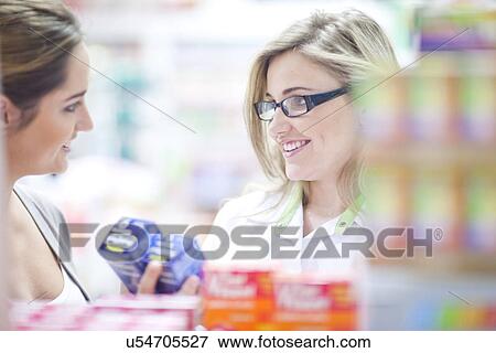 Pharmacist talking to customer, holding boxes of vitamins View Large Photo Image Stock Photo - Pharmacist talking to customer, holding boxes of vitamins. Fotosearch