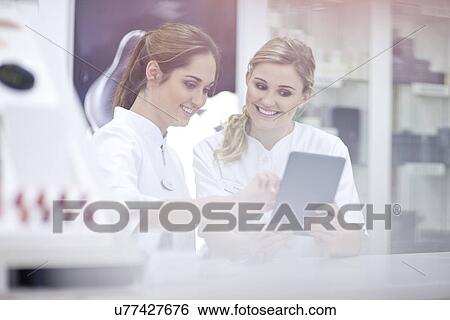 Stock Photograph - Pharmacists having conversation, using digital tablet. Fotosearch