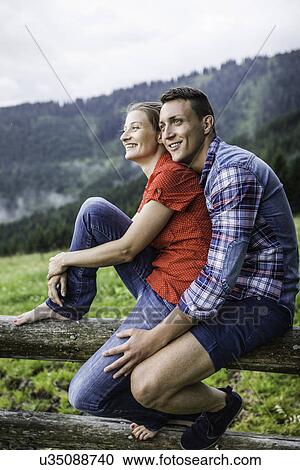 Stock Image - Portrait of couple sitting on fence, Tyrol Austria. Fotosearch
