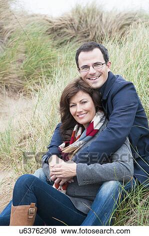 Portrait of couple sitting on sand dune View Large Photo Image Stock Photo - Portrait of couple sitting on sand dune. Fotosearch