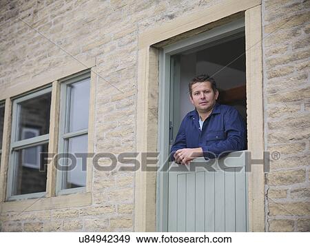 Stock Photo - Portrait of farmer looking out from farmhouse door. Fotosearch