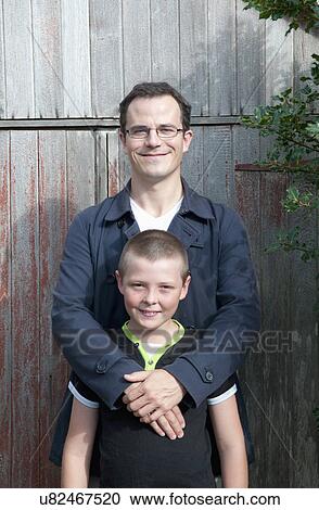 Stock Image - Portrait of father and son in garden. Fotosearch