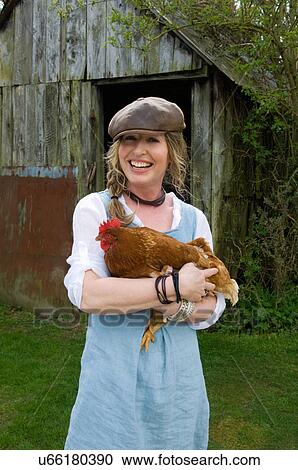 Stock Image - Portrait of female farmer holding hen. Fotosearch
