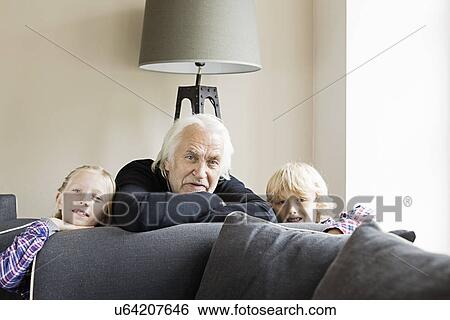 Portrait of grandfather and grandchildren leaning on sofa View Large Photo Image Stock Photograph - Portrait of grandfather and grandchildren leaning on sofa. Fotosearch
