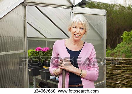 Stock Photo - Portrait of mature woman by greenhouse. Fotosearch