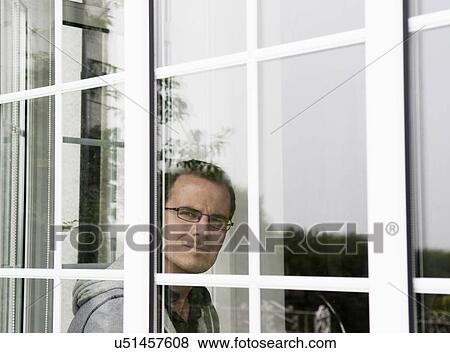 Stock Photo - Portrait of mid adult man looking out of window. Fotosearch