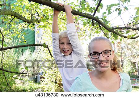 Stock Image - Portrait of sister and brother in garden. Fotosearch