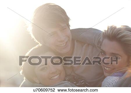 Stock Image - Portrait of three friends huddled up in blanket. Fotosearch